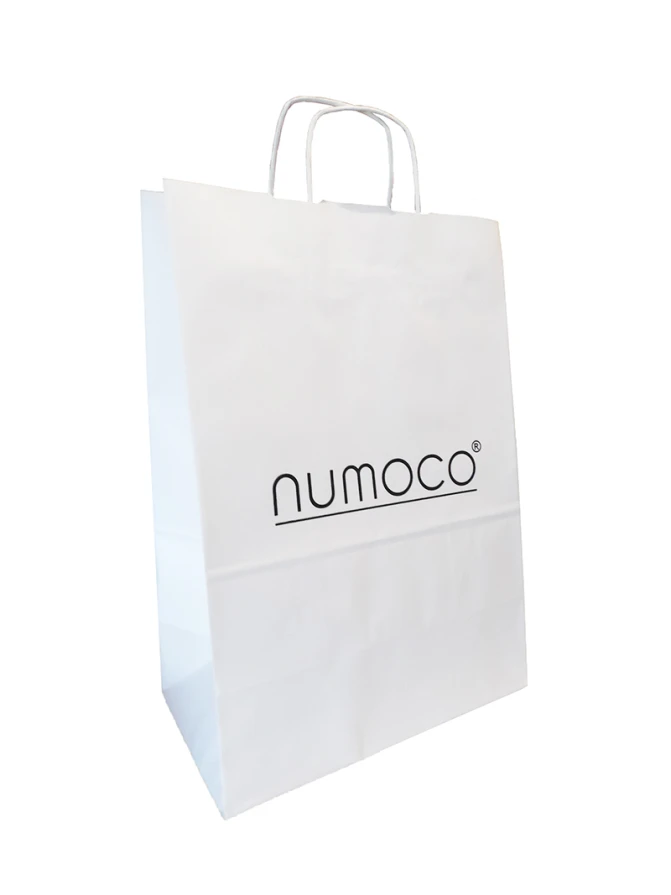 Balta popierinė maišelis su juodu logotipu „numoco“ centre. Maišelis turi tvirtas popierines rankenas, tinkamas patogiam nešiojimui.