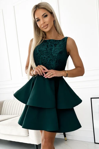 Elegantiška, tamsiai žalia suknelė su dvigubu klostuotu sijonu ir subtiliu raštu viršutinėje dalyje. Suknelė puikiai tinka ypatingoms progoms, suteikianti rafinuotumo ir žavesio.}
