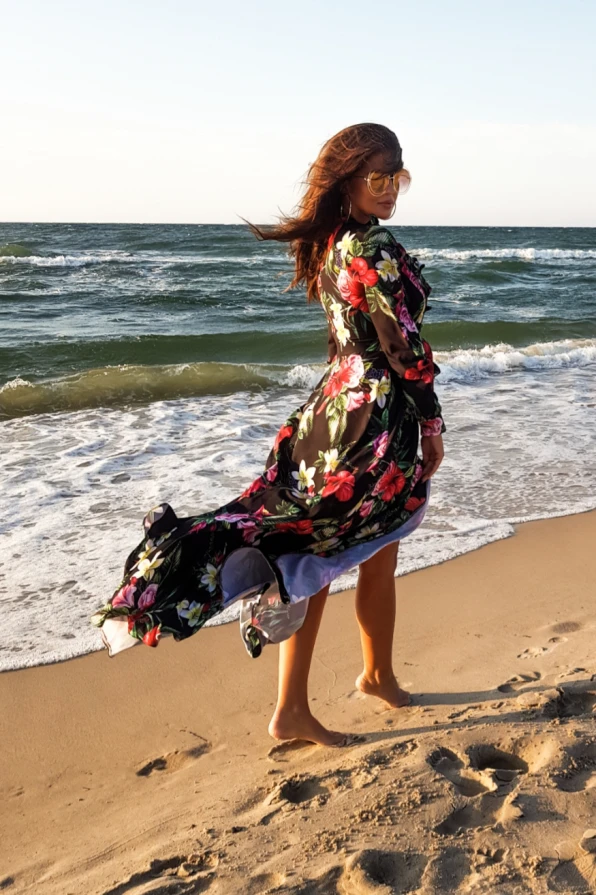 Moteriška maxi suknelė su gėlių raštu ir elegantiškais raukiniais, puikiai tinkanti vasaros pasivaikščiojimams paplūdimyje. Suknelė pasižymi lengvumu ir spalvingumu, suteikiančiu žaismingumo ir stiliaus.