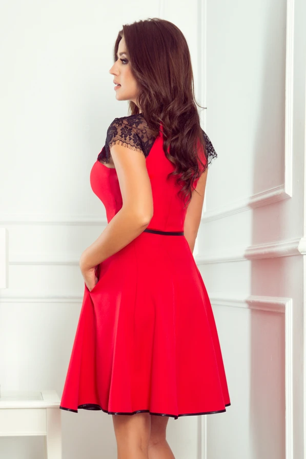 Raudona suknelė su juodais nėriniais ant pečių suteikia elegancijos ir rafinuotumo. Suknelė yra prigludusi viršuje ir platėjanti apačioje, pabrėžianti moterišką siluetą.