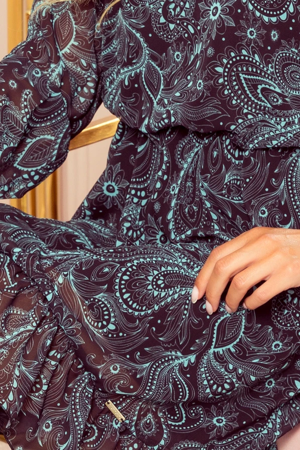 Moteriška suknelė iš lengvo šifono su elegantišku paisley raštu, dominuojančiu tamsiai mėlynos ir turkio spalvų deriniu. Suknelė pasižymi laisvu kirpimu ir ilgomis rankovėmis, suteikiančiomis rafinuotumo ir komforto.
