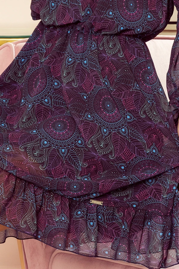 Elegantiška, lengva suknelė iš šifono su ryškiu, etniniu raštu, dominuojančios tamsiai violetinės ir mėlynos spalvos. Suknelė turi subtilų klostuotą kraštą, suteikiantį jai žaismingumo ir elegancijos.