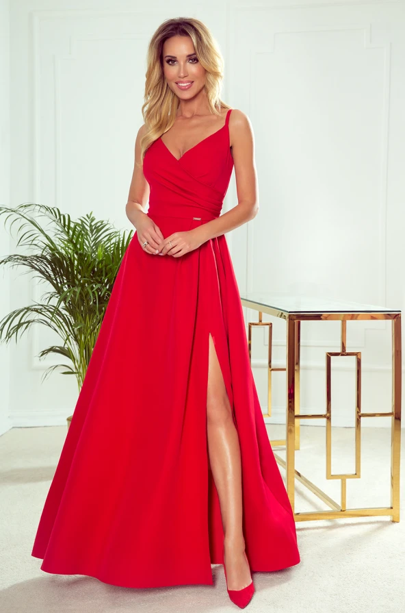 Elegantiška raudona maxi suknelė su plonu dirželiu ir gilia iškirpte, pabrėžiančia figūrą. Suknelė turi aukštą skeltuką, suteikiantį drabužiui žavesio ir elegancijos.