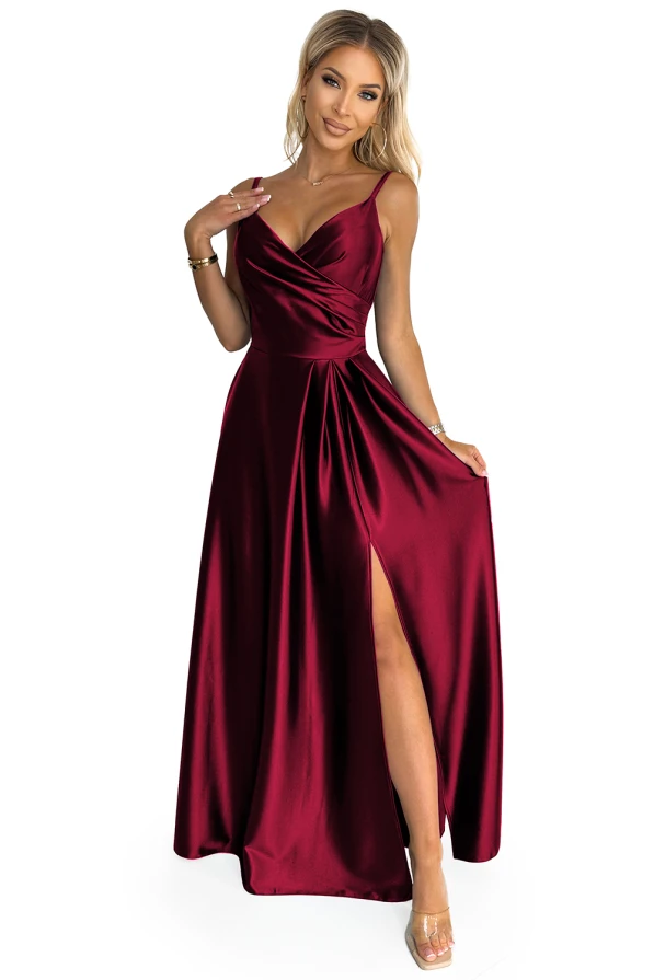 Elegantiška ilga bordo spalvos suknelė su plonu dirželiu ir gilia iškirpte. Suknelė turi subtilų skeltuką, kuris suteikia žavesio ir elegancijos.