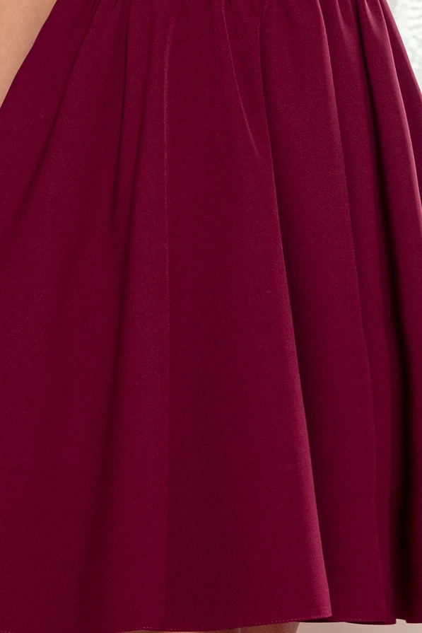 Bordo spalvos suknelė su elegantiškomis klostėmis ir subtiliomis raukšlėmis. Audinys atrodo minkštas ir švelnus, suteikiantis prabangos pojūtį.