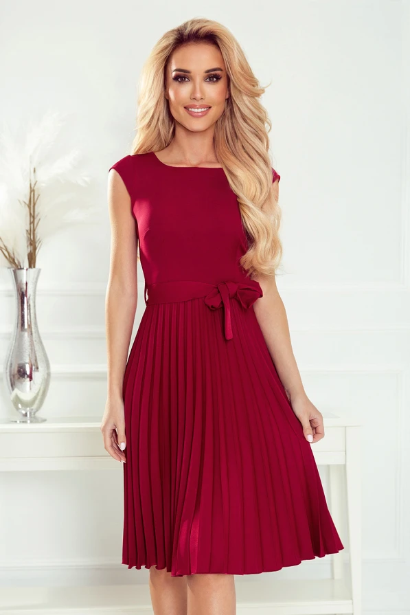 Elegantiška, raudona, plisuota suknelė su kaspinu ties juosmeniu suteikia rafinuotumo ir moteriškumo. Suknelė puikiai tinka tiek kasdienai, tiek ypatingoms progoms.