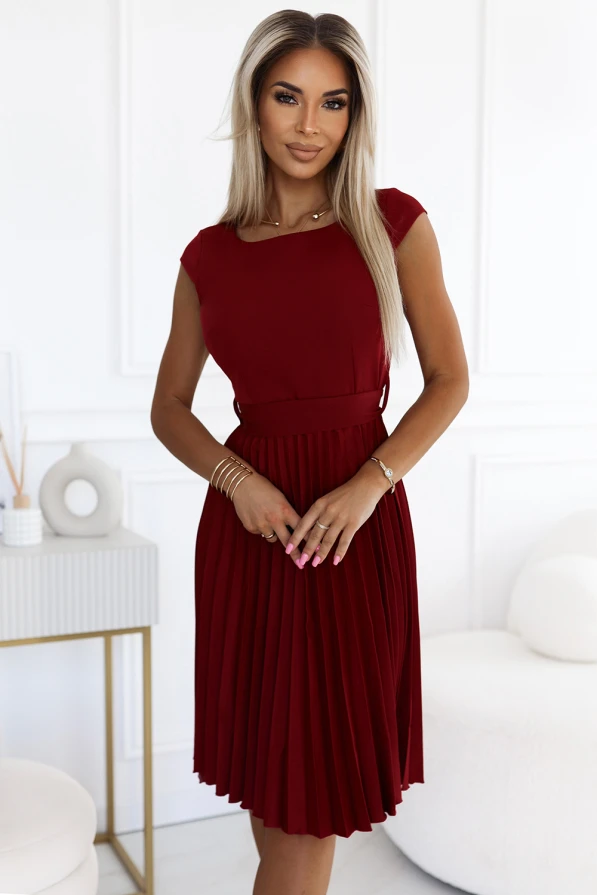 Elegantiška, raudona, plisuota suknelė su trumpomis rankovėmis ir apvalia iškirpte. Suknelė puikiai tinka tiek kasdienai, tiek ypatingoms progoms, suteikdama rafinuotumo ir stiliaus.