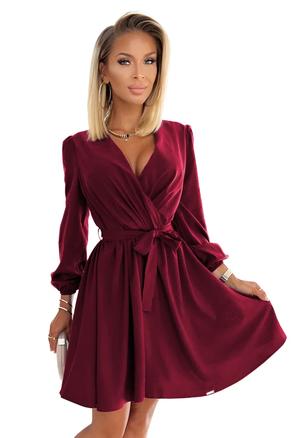 Elegantiška bordo spalvos suknelė su V formos iškirpte ir ilgesnėmis rankovėmis, pabrėžianti moteriškumą. Suknelė turi juosmenį pabrėžiantį diržą, suteikiantį elegancijos ir stiliaus.