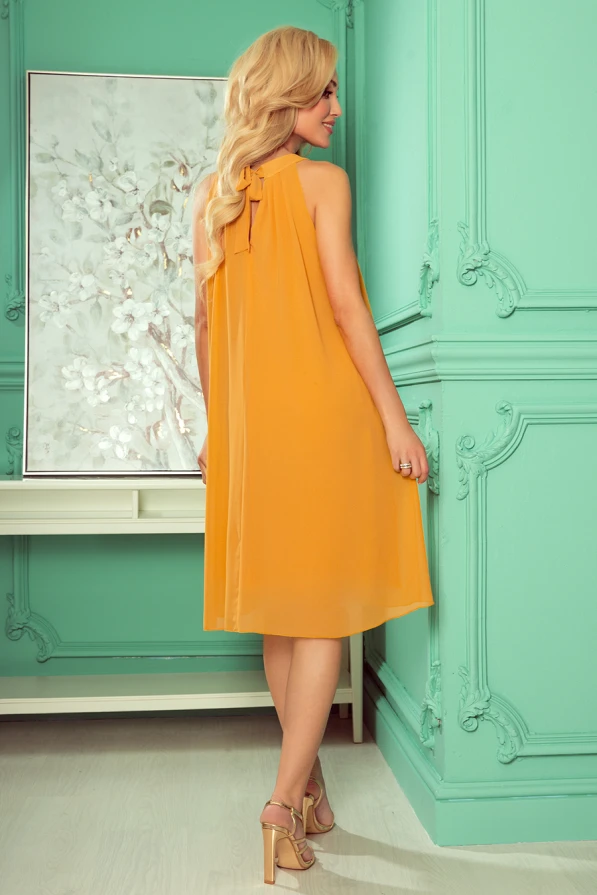 Elegantiška, šifoninė suknelė garstyčių spalvos, su kaspinu ant kaklo, suteikianti lengvumo ir elegancijos pojūtį. Suknelė puikiai tinka vasaros renginiams ar ypatingoms progoms.