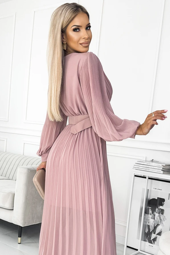 Moteriška suknelė su plisuotu dizainu, švelnios rožinės spalvos, suteikia elegancijos ir rafinuotumo. Suknelė turi ilgomis rankovėmis ir diržą, pabrėžiantį liemenį.