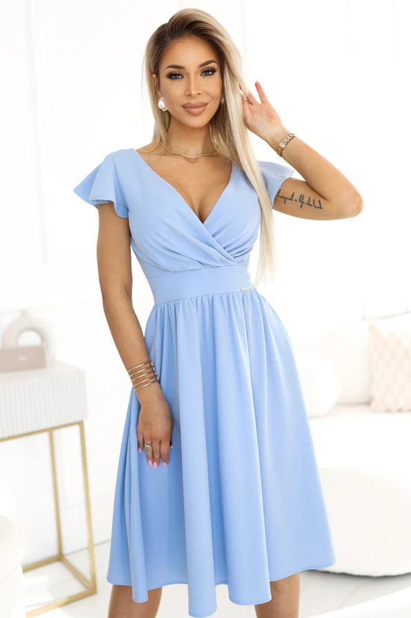 Mėlyna suknelė su V formos iškirpte ir trumpomis rankovėmis suteikia elegancijos ir moteriškumo. Suknelė puikiai tinka tiek kasdienai, tiek ypatingoms progoms.