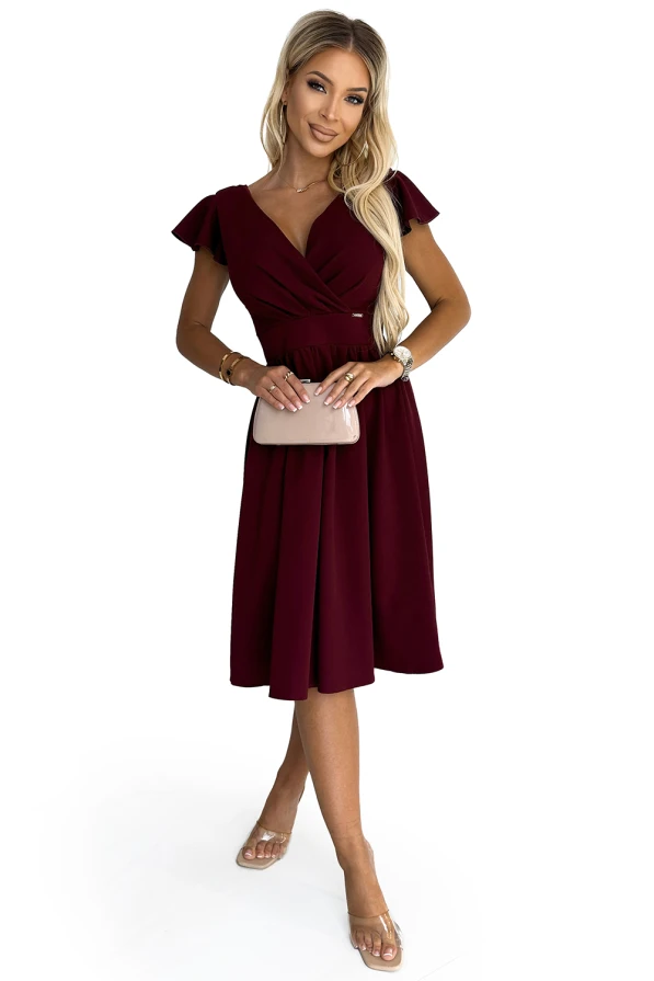 Elegantiška bordo spalvos suknelė su trumpomis rankovėmis ir klostuotu sijonu suteikia rafinuotumo ir moteriškumo. Suknelė puikiai tinka ypatingoms progoms, pabrėžiant figūrą ir suteikiant elegancijos.