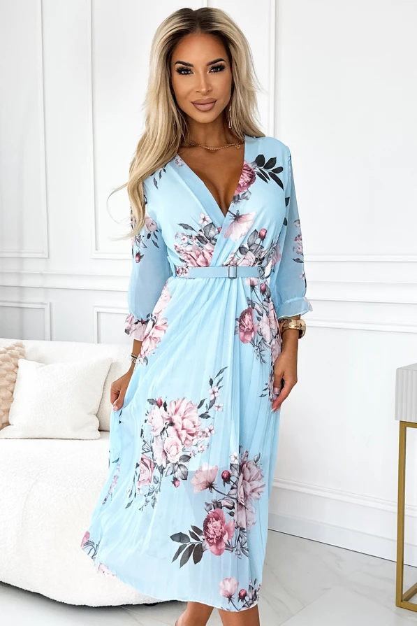 Mėlyna plisuota suknelė su gėlių raštais ir dirželiu, suteikianti elegancijos ir moteriškumo. Suknelė turi V formos iškirptę ir trijų ketvirčių rankoves, puikiai tinkančias pavasario ar vasaros sezonui.