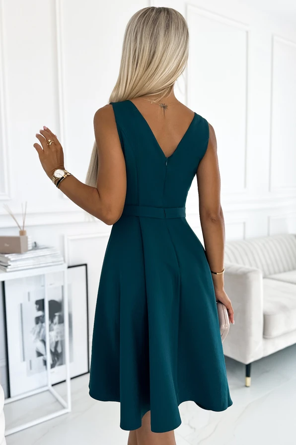 Elegantiška, tamsiai žalia suknelė be rankovių su V formos iškirpte nugaroje. Suknelė subtiliai priglunda prie liemens ir lengvai krenta žemyn, suteikdama elegancijos ir rafinuotumo.