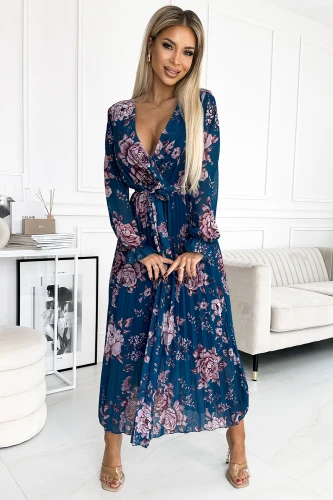 Elegantiška ilga suknelė su gėlių raštu, pagaminta iš plisuoto šifono, suteikia lengvumo ir moteriškumo įspūdį. Suknelė turi V formos iškirptę ir ilgomis rankovėmis, puikiai tinka tiek kasdienai, tiek ypatingoms progoms.}