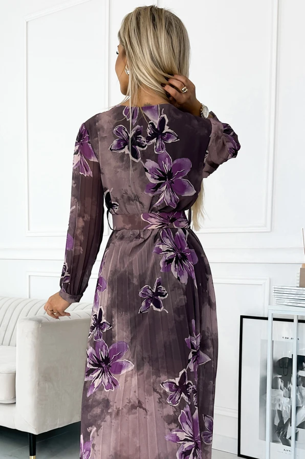 Ilga, plisuota šifoninė suknelė su ilgomis rankovėmis ir violetiniais gėlių raštais. Suknelė suteikia elegancijos ir lengvumo, puikiai tinka ypatingoms progoms.