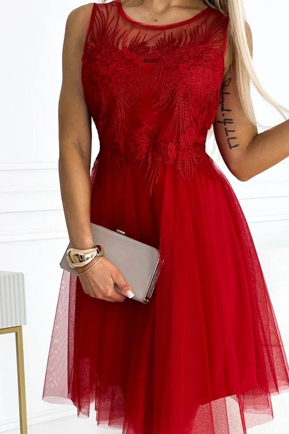 Elegantiška raudona suknelė su subtiliais nėriniais ir tiulio sijonu suteikia moteriškumo ir rafinuotumo. Suknelė puikiai tinka ypatingoms progoms, pabrėžiant eleganciją ir stilių.