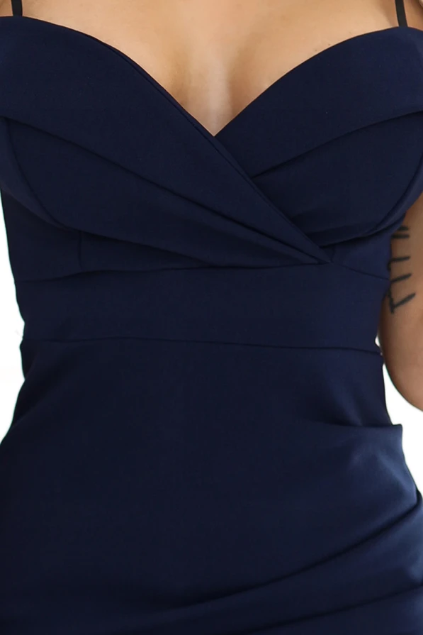 Elegantiška tamsiai mėlyna midi suknelė su plonomis petnešėlėmis ir subtiliu, prigludusiu siluetu. Suknelė pasižymi elegantišku dizainu, kuris pabrėžia moterišką figūrą.
